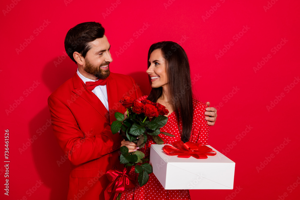 Photo portrait of lovely young couple hug shoulders surprise valentine day dressed stylish elegant outfit isolated on red color background Photo portrait of lovely young couple hug shoulders surprise valentine day dressed stylish elegant outfit isolated on red color background