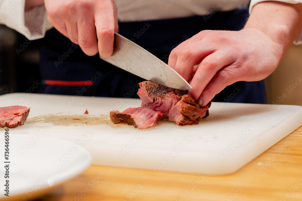 close-up of professional cutting seared beef steak with knife white board