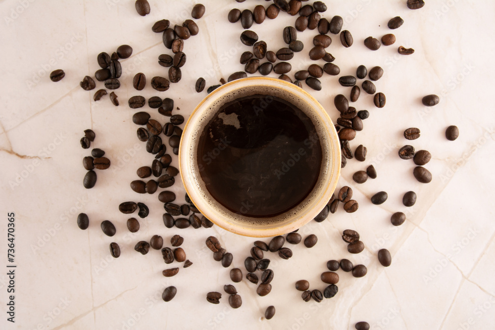 Coffee mug in a marbled stone background with coffee beans marble surface in aerial view Coffee mug in a marbled stone background with coffee beans marble surface in aerial view