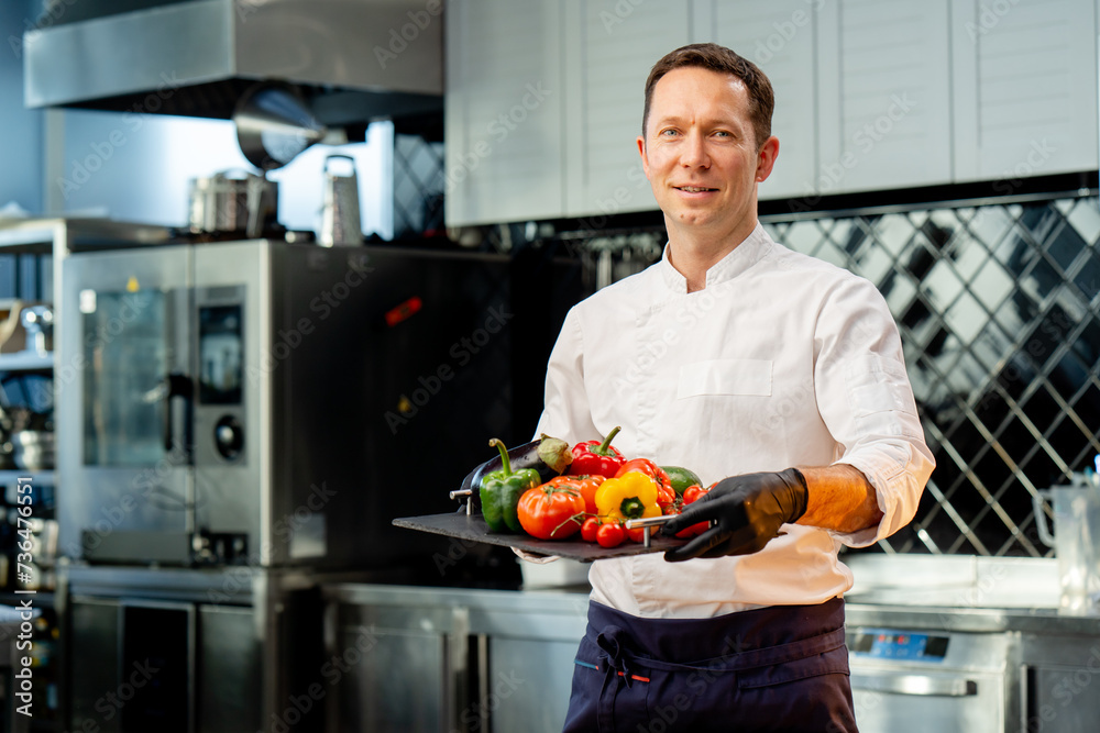 chef holding a tray with different washed vegetables ready use colorful vegetables in the kitchen