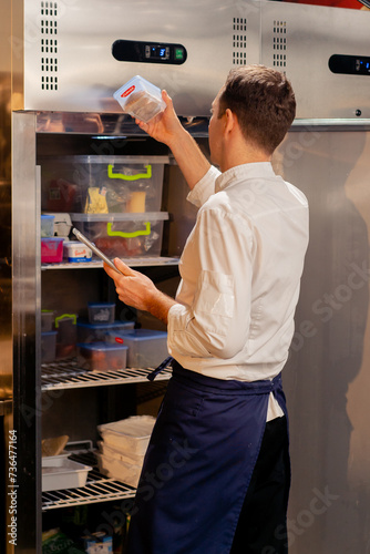 professional kitchen chef looks into the fridge and chooses ingredients for cooking food concept