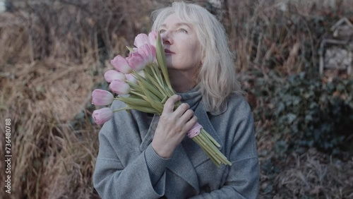An elegant mature woman with flowers on the bench