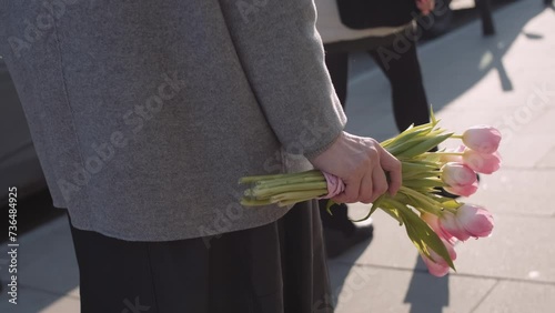 An elegant woman walking down the street with a bouquet of pink tulips