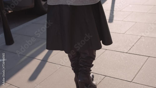 An elegant woman walking down the street with a bouquet of pink tulips