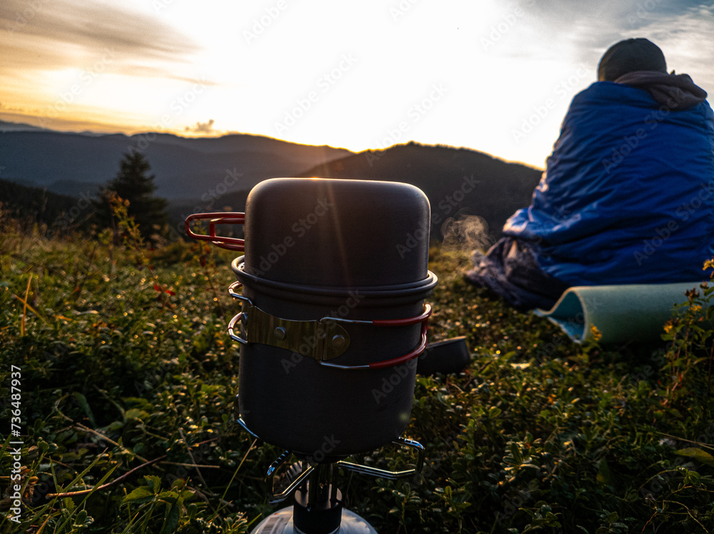 Gas burner and tourist sitting on the grass