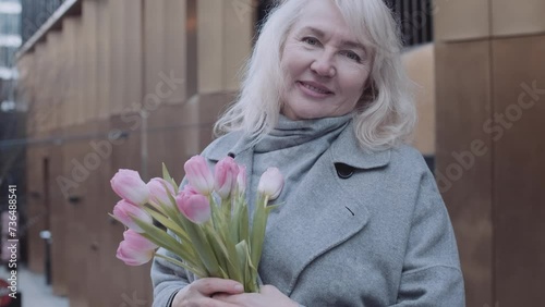 A mature elegant woman with a bouquet of pink tulips