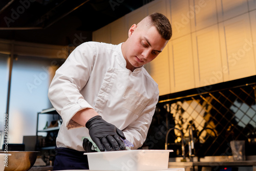 close-up of a chef in the kitchen in white jacket grating beets on the table