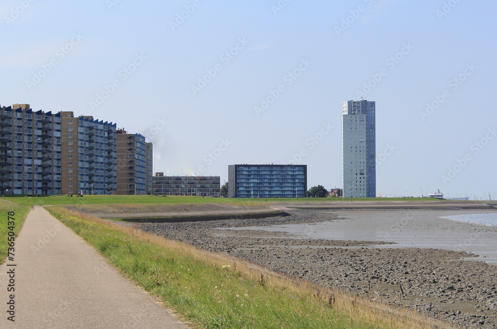 the boulevard of the port city Terneuzen with flats and a residential tower behind the seawall of the westerschelde sea