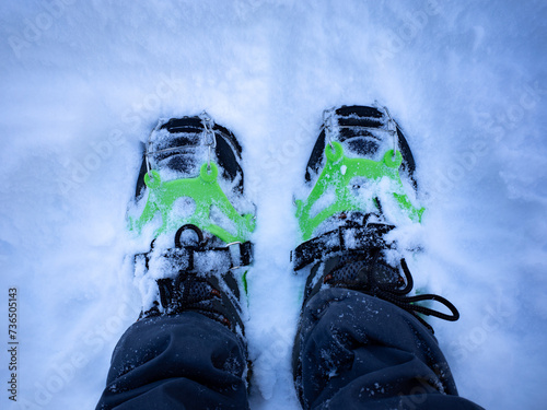A top-down close-up view of mountaineering crampons on fresh snow