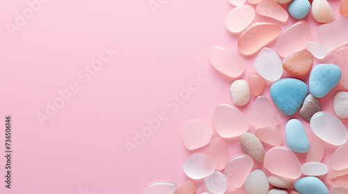 Polish textured sea glass and stones on pink background. Top view with copy space