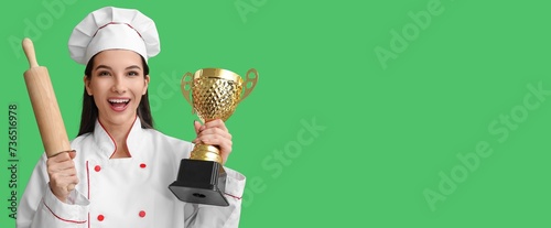 Female chef with trophy cup and rolling pin on green background with space for text photo