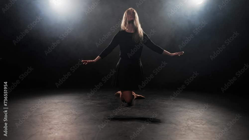 Middle aged woman choreographer dancing. Blonde hard-working female ballerina dances in black dress in studio on black background. Perform dance element of classical ballet. Professional choreography. Middle aged woman choreographer dancing. Blonde hard-working female ballerina dances in black dress in studio on black background. Perform dance element of classical ballet. Professional choreography.