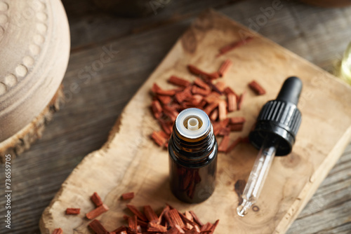 A bottle of essential oil with red sandalwood chips