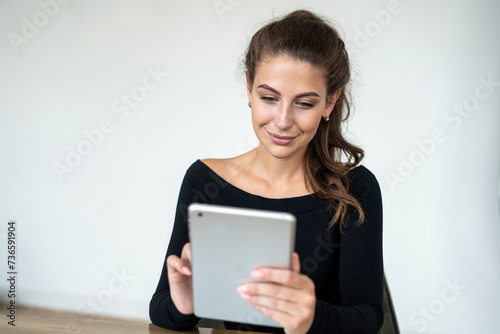 Concentrated young woman browsing on a tablet, engaged in digital communication.