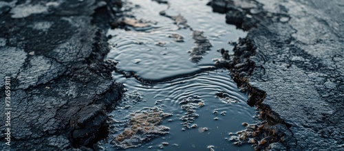 Oil spills contaminate wet asphalt, highlighting environmental pollution.
