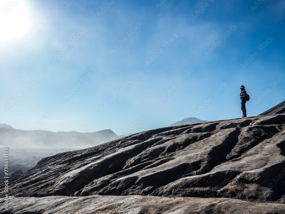 A person stands on the volcanic terrain of dried lava in Bromo Tengger Semeru National Park, East Java, Indonesia.