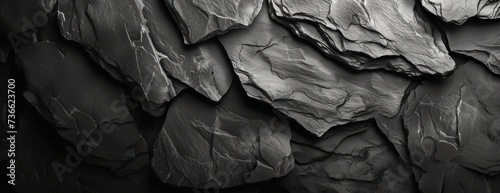 A dark grey black slate background filled with a range of rock formations in black and white. photo