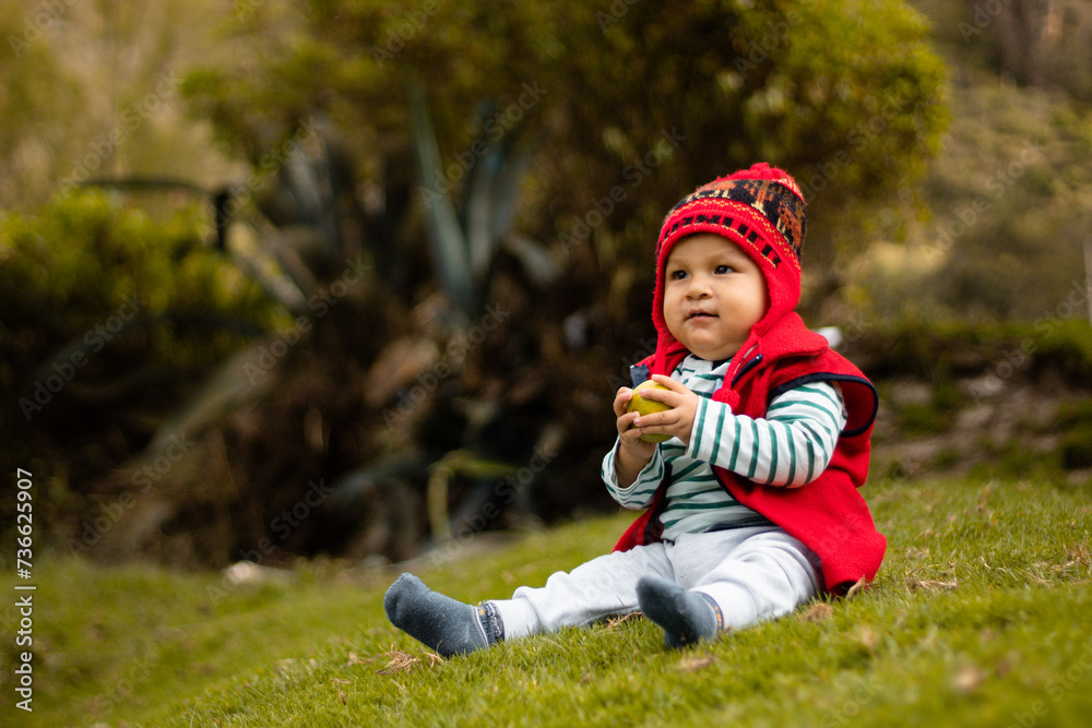 Un bebé sonriente con su chullo tejido, disfrutando del sabor de la naranja, pequeño tesoro andino, estilo de vida saludable, quechua, al aire libre Un bebé sonriente con su chullo tejido, disfrutando del sabor de la naranja, pequeño tesoro andino, estilo de vida saludable, quechua, al aire libre