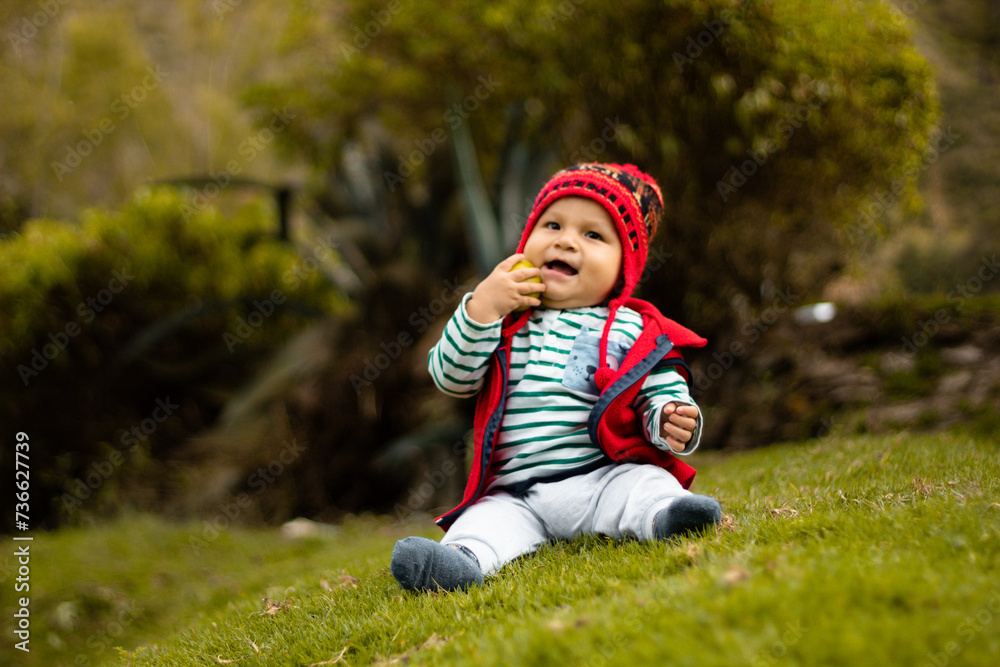 Un bebé sonriente con su chullo tejido, disfrutando del sabor de la naranja, pequeño tesoro andino, estilo de vida saludable, quechua, al aire libre Un bebé sonriente con su chullo tejido, disfrutando del sabor de la naranja, pequeño tesoro andino, estilo de vida saludable, quechua, al aire libre