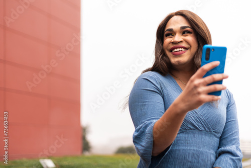 Close-up portrait of trans woman using cellphone and laughing photo