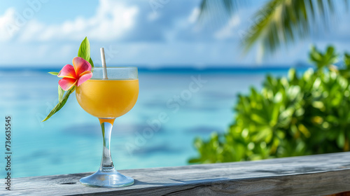 A glass of summer cocktail with the sea and blue sky in the background