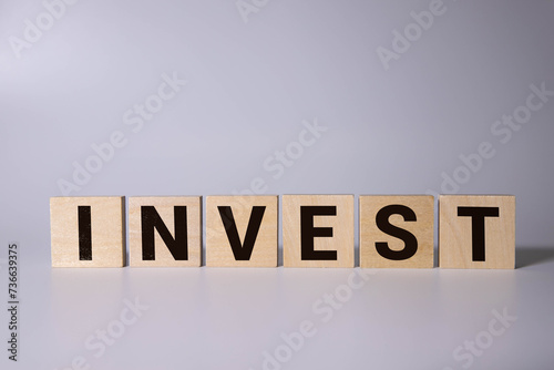 The word invest on wooden cubes against yellow background.