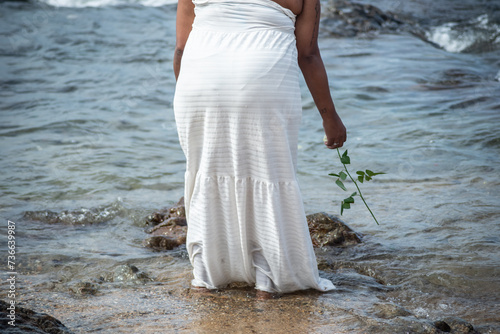 A person who is a fan of Candomble is seen entering the water on the beach to pay homage to Iemanja. City of Salvador, Bahia. photo