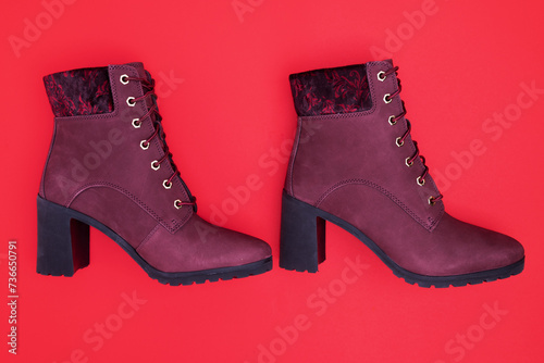 pair of red of suede women's half-boots with high heels on a red background. Stylish demi-season women's shoes.
