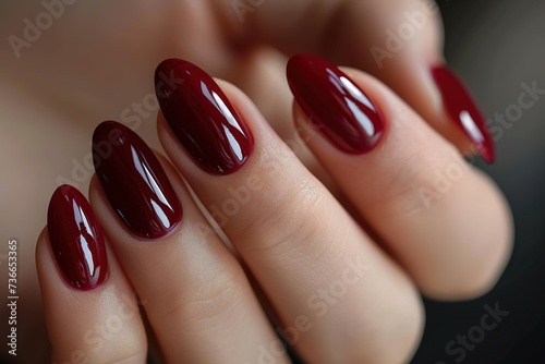 Woman hand with burgundy color nail polish on her fingernails. Burgundy nail manicure with gel polish at luxury beauty salon. Nail art and design. Female hand model. French manicure.