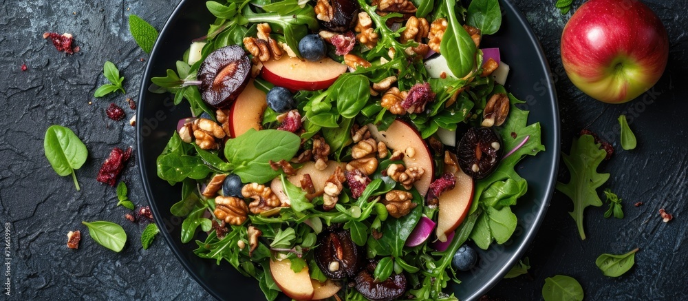 Nutritious salad with greens, plums, nuts, and apple.