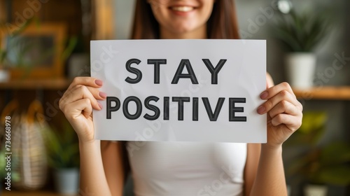 Motivational success concept woman holding stay positive sign on abstract blurred background