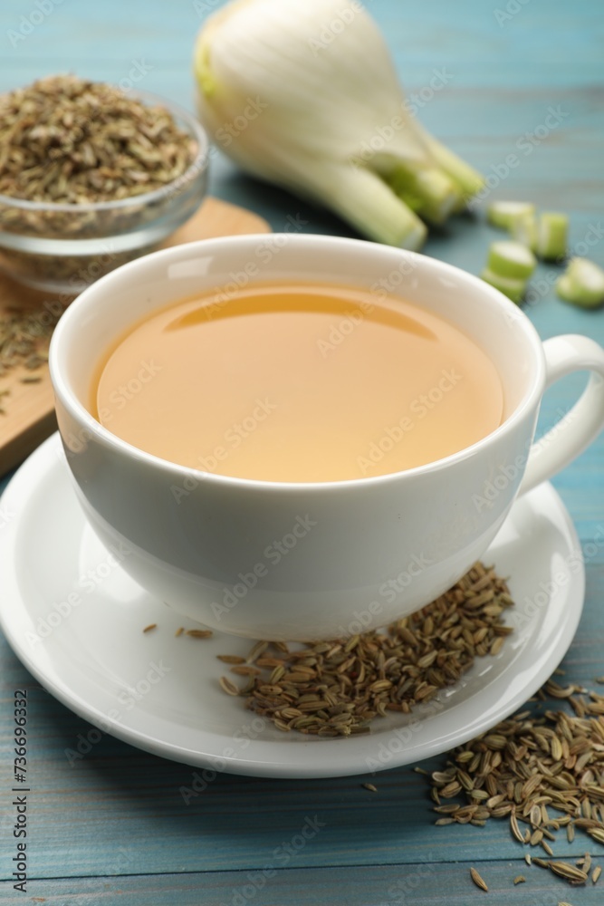 Fennel tea in cup, seeds and fresh vegetable on light blue wooden table, closeup Fennel tea in cup, seeds and fresh vegetable on light blue wooden table, closeup