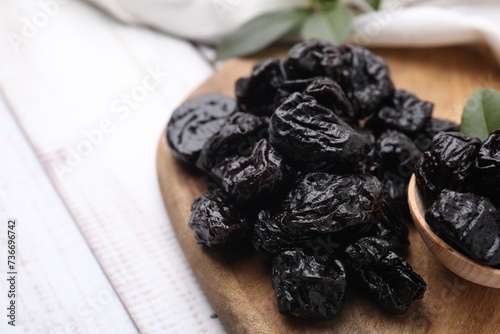 Tasty dried prunes on light wooden table, closeup. Space for text