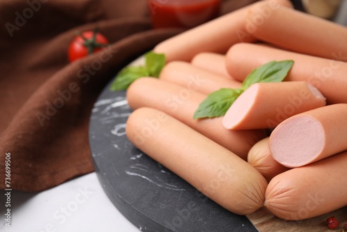 Delicious boiled sausages and basil on table, closeup