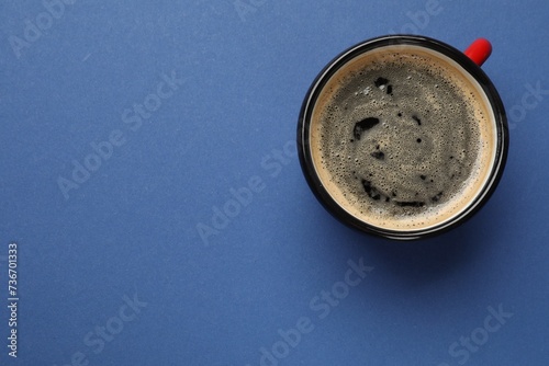 Fresh coffee in cup on blue background, top view. Space for text