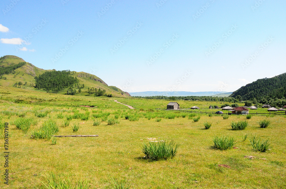 A small farm with traditional buildings and a wooden fence in a picturesque valley surrounded by high hills.