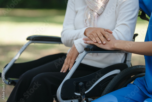 Compassionate Asian woman provides care to  elderly person in wheelchair outdoors. Engaging in physical therapy, happiness, encouraging positive environment for mature individuals with grey hair. © makibestphoto