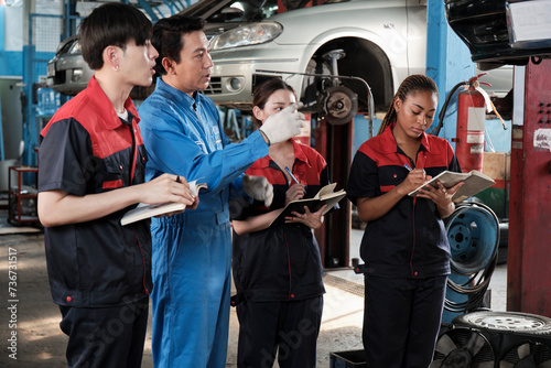 Specialist lecture. Male supervisor engineer describe automotive suspension fixing with mechanic worker staff teams for repair work at car service garage and maintenance jobs in automobile industry.