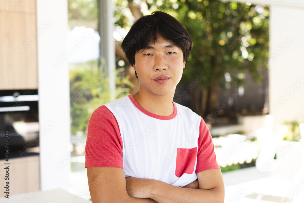 Teenage Asian boy stands confidently at home, arms crossed Teenage Asian boy stands confidently at home, arms crossed