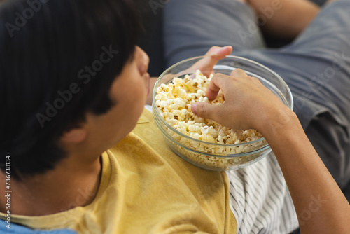 Teenage Asian boy enjoys a bowl of popcorn at home photo