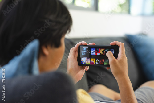 Teenage Asian boy browses a video streaming site on a smartphone at home photo