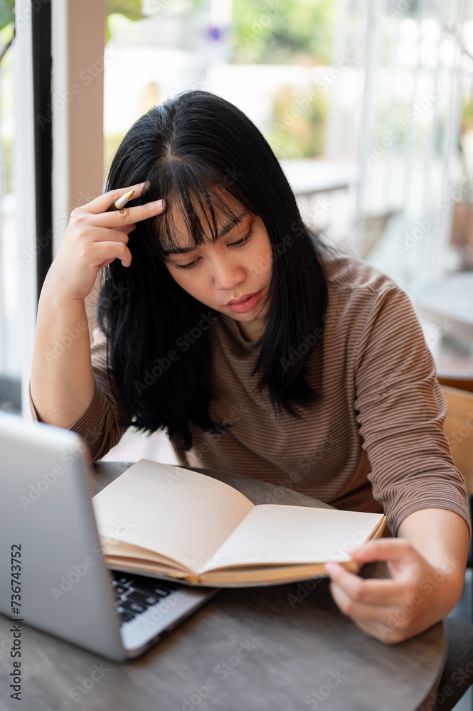 A serious and concentrated young Asian woman is reading a book in a cafe. A serious and concentrated young Asian woman is reading a book in a cafe.