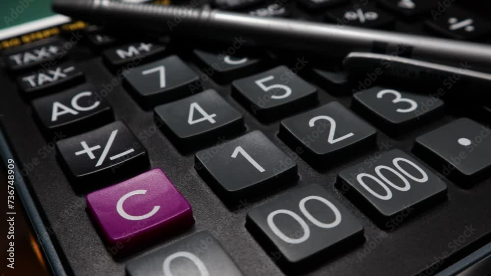 A closeup clip of a larg size buttons calculator with a pen, rotating on an automatic display stand. A closeup clip of a larg size buttons calculator with a pen, rotating on an automatic display stand.