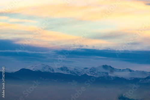 an airplane flies over the mountains with snow on the peaks © Wirestock