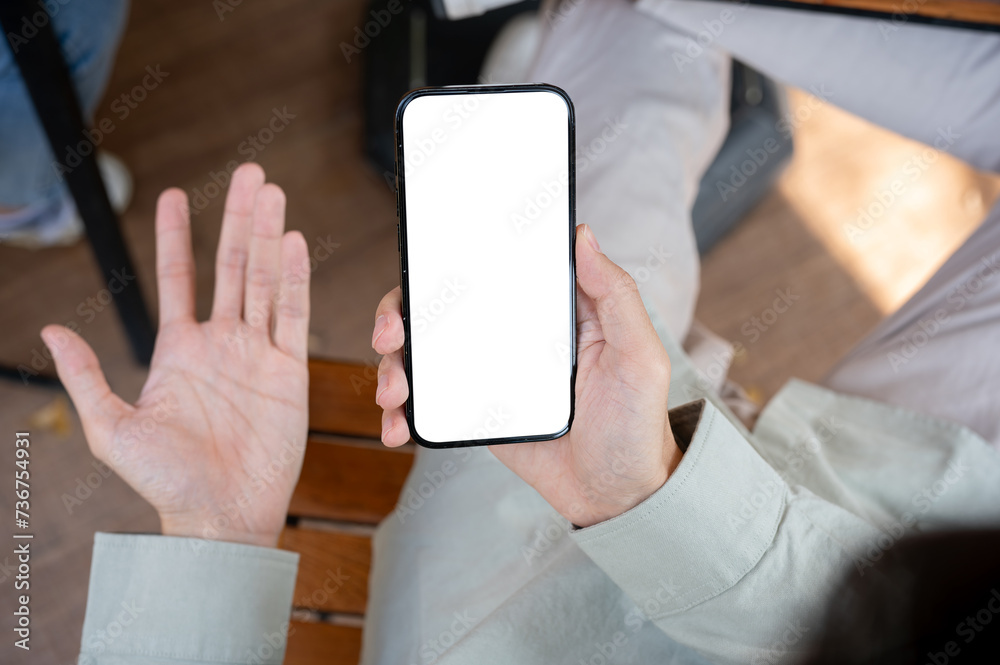 An unhappy, dissatisfied man showing his palm while using his smartphone at a table indoors. An unhappy, dissatisfied man showing his palm while using his smartphone at a table indoors.