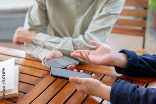 Two people sharing contact info or transferring files by bringing two smartphones close together.