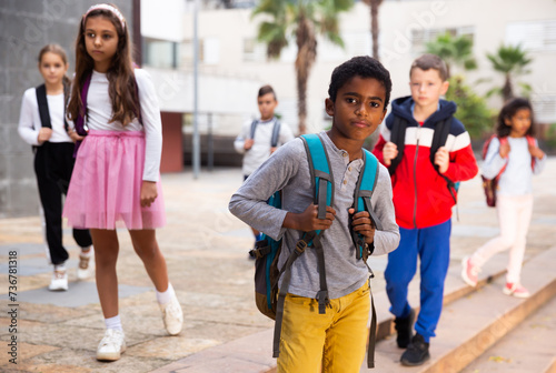 Obraz na płótnie Preteen mulatto boy with rucksack walking outdoors on his way to school on warm autumn day