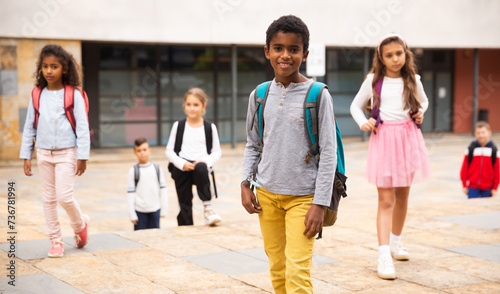 Obraz na plátně Preteen mulatto boy with rucksack walking outdoors on his way to school on warm autumn day