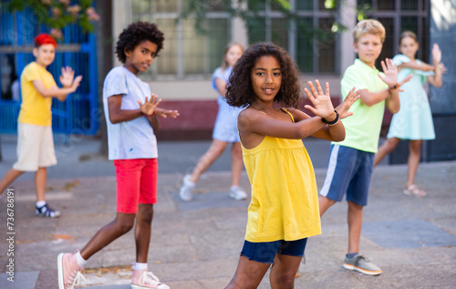 Positive african-american girl performing street dance with her friends outdoors.