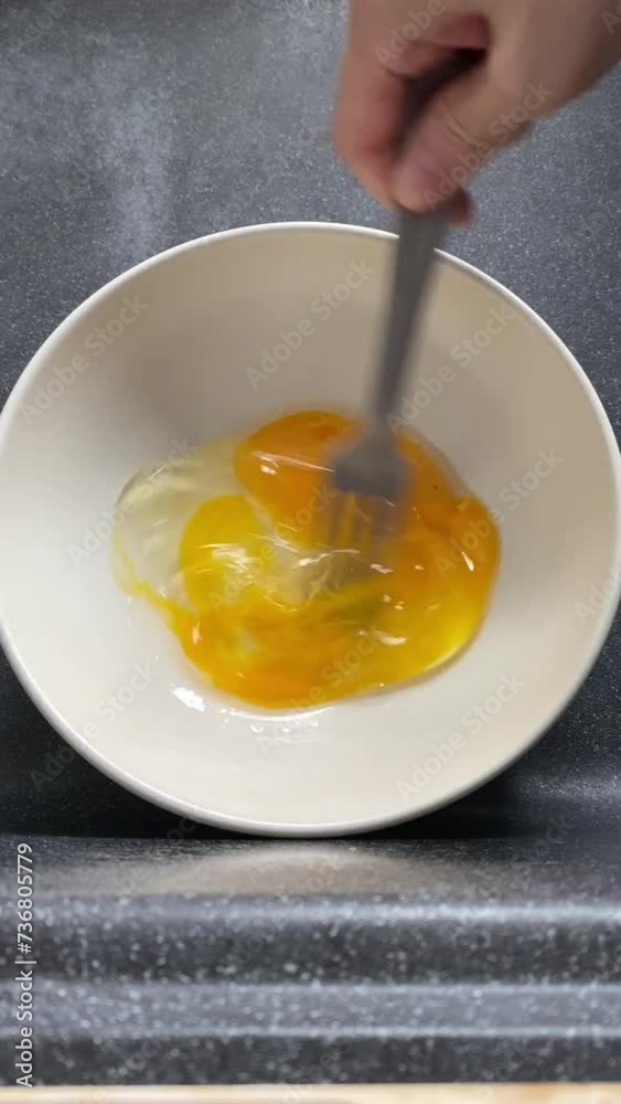Top down view of hand whisking, beating raw egg in a white ceramic bowl in fast circular motion. Clip starts with intact perfect raw egg. Top down view of hand whisking, beating raw egg in a white ceramic bowl in fast circular motion. Clip starts with intact perfect raw egg.